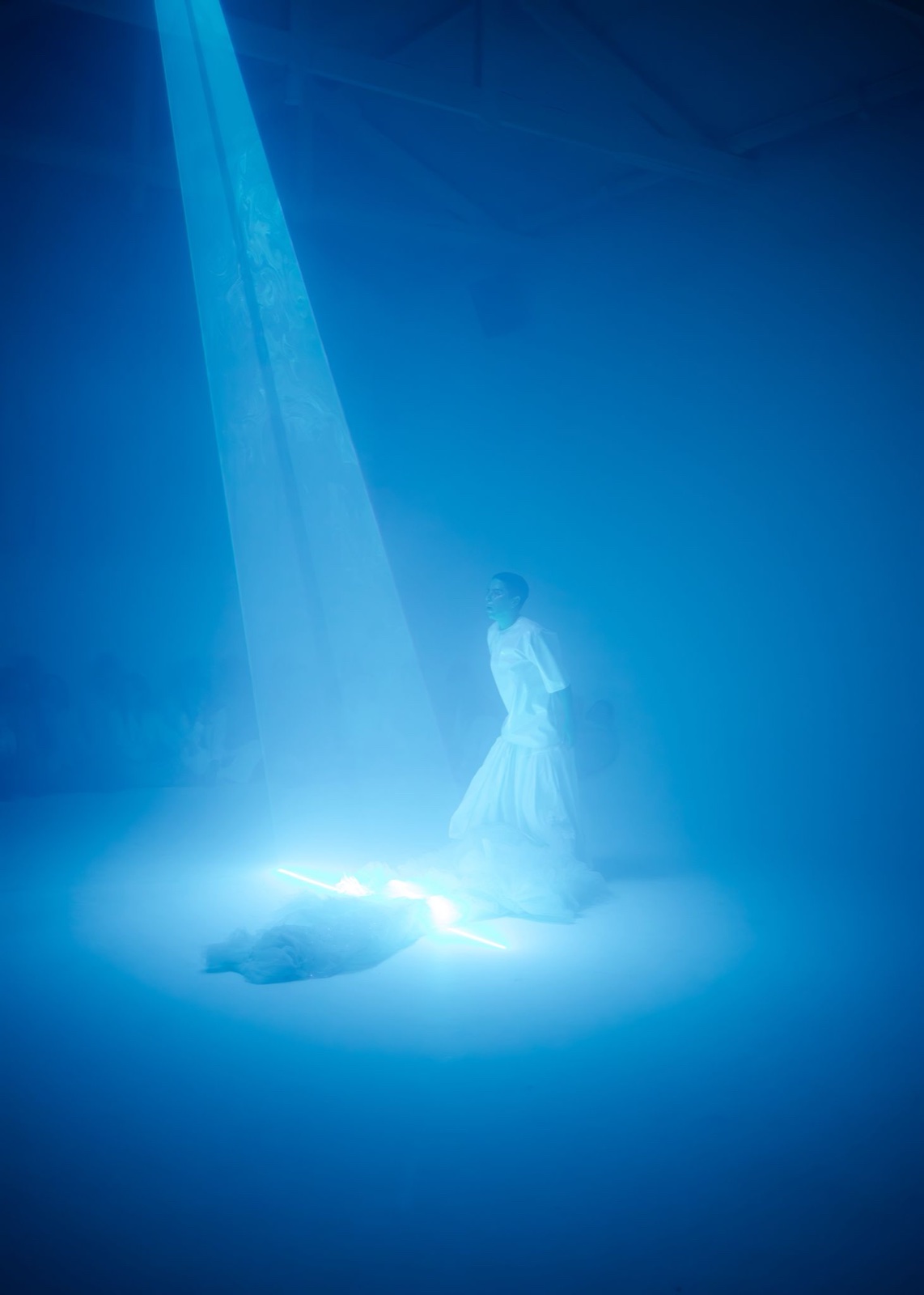 Performer in deep blue light with hanging fabric beam